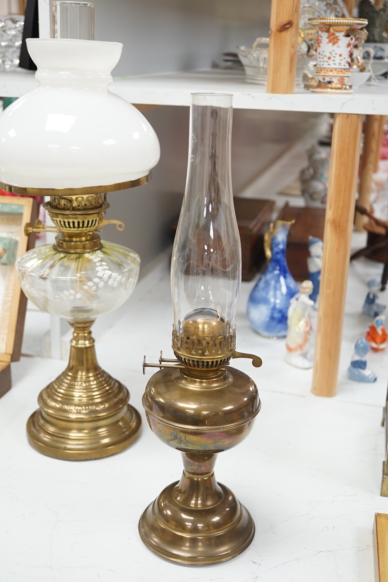 A late 19th century brass oil lamp with painted bowl and opaque shade together with a later oil lamp, largest 59cm high. Condition - fair to good